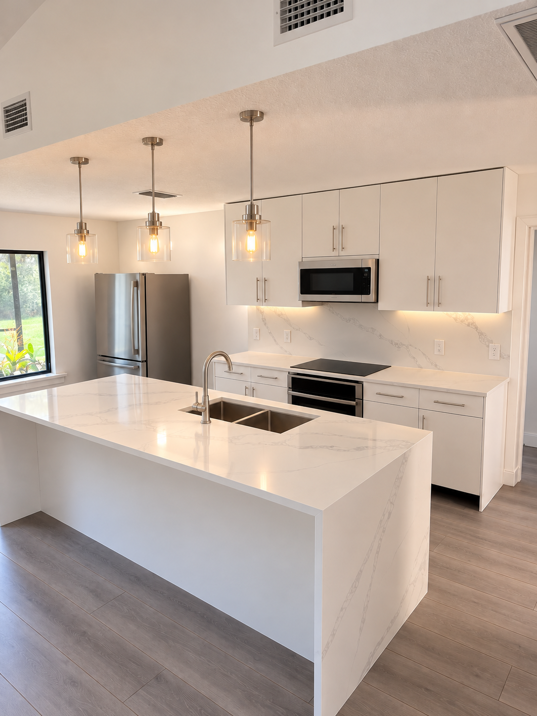White kitchen with an island, pendant lights, and stainless steel appliances